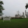 A rusting Nova chemical factory sits next to the entrance to Aamjiwnaang First Nation. The sign reads: Where Opportunity Begins. Published in The Ecologist, December 1, 2006.