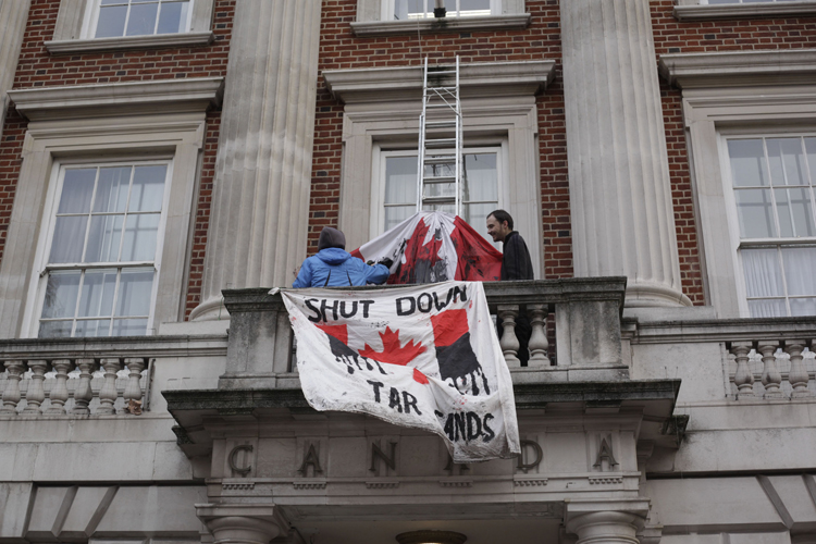 On December 15, during COP15 in Copenhagen, activists in London, England scaled the Canadian High Commission, dunked the Canadian flag in oil, and strung up a banner of their own. Photo Credit: Nick Cobbing